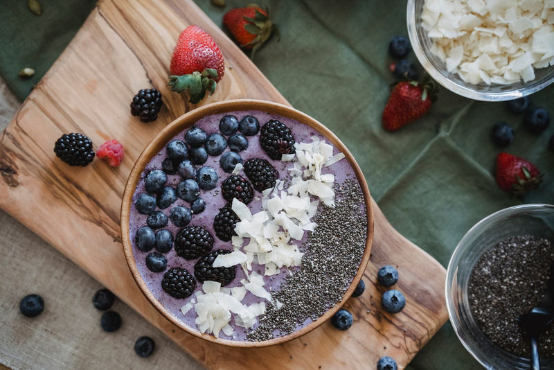 Bol de desayuno con frutos rojos sobre una tabla de madera
